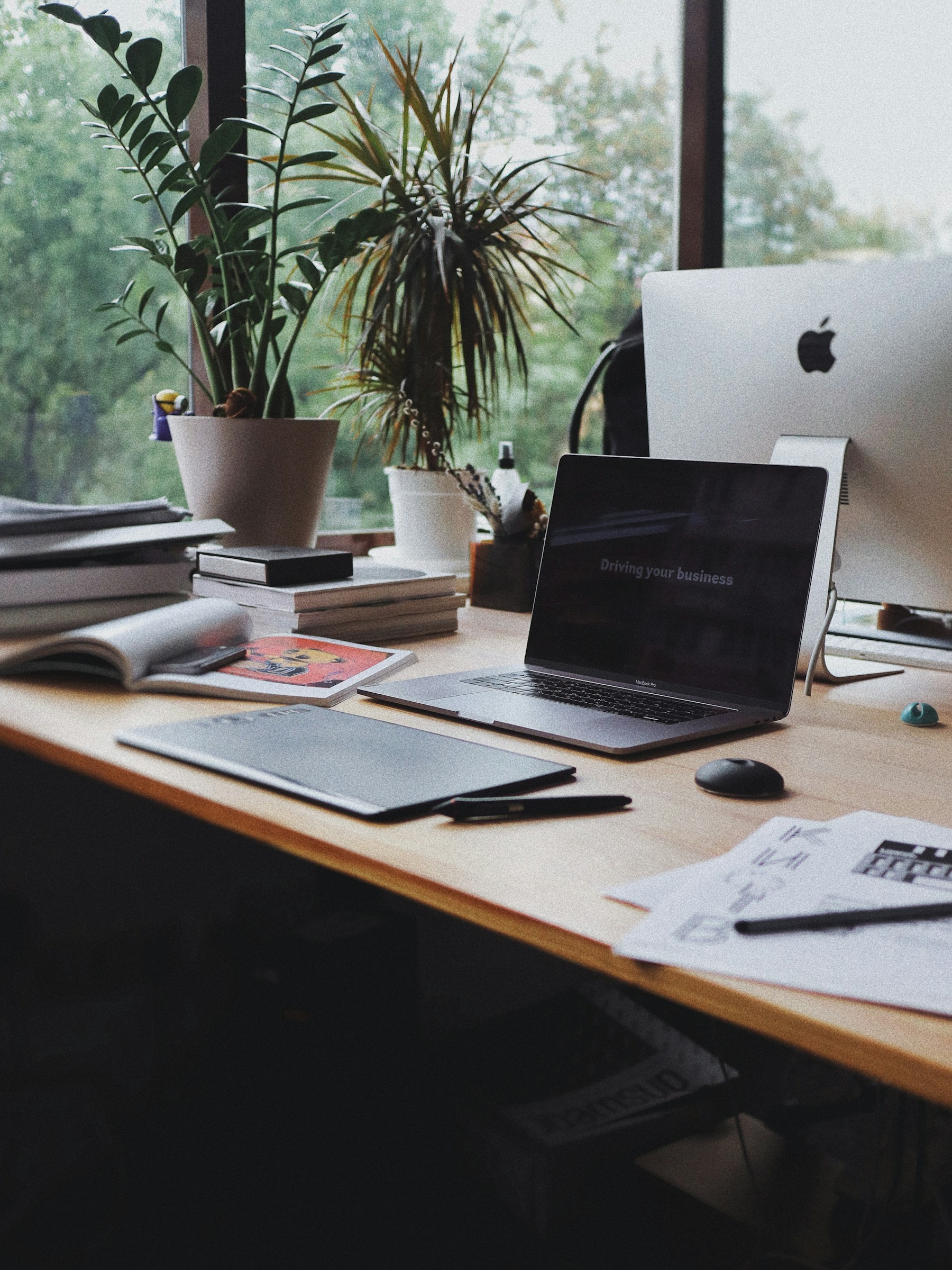 Design workspace with a notebook, laptop, and printed material